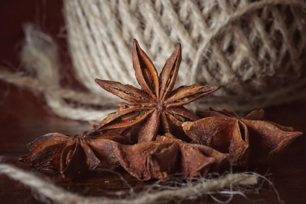 Close-up of star anise pods on a wooden surface with twine in the background.